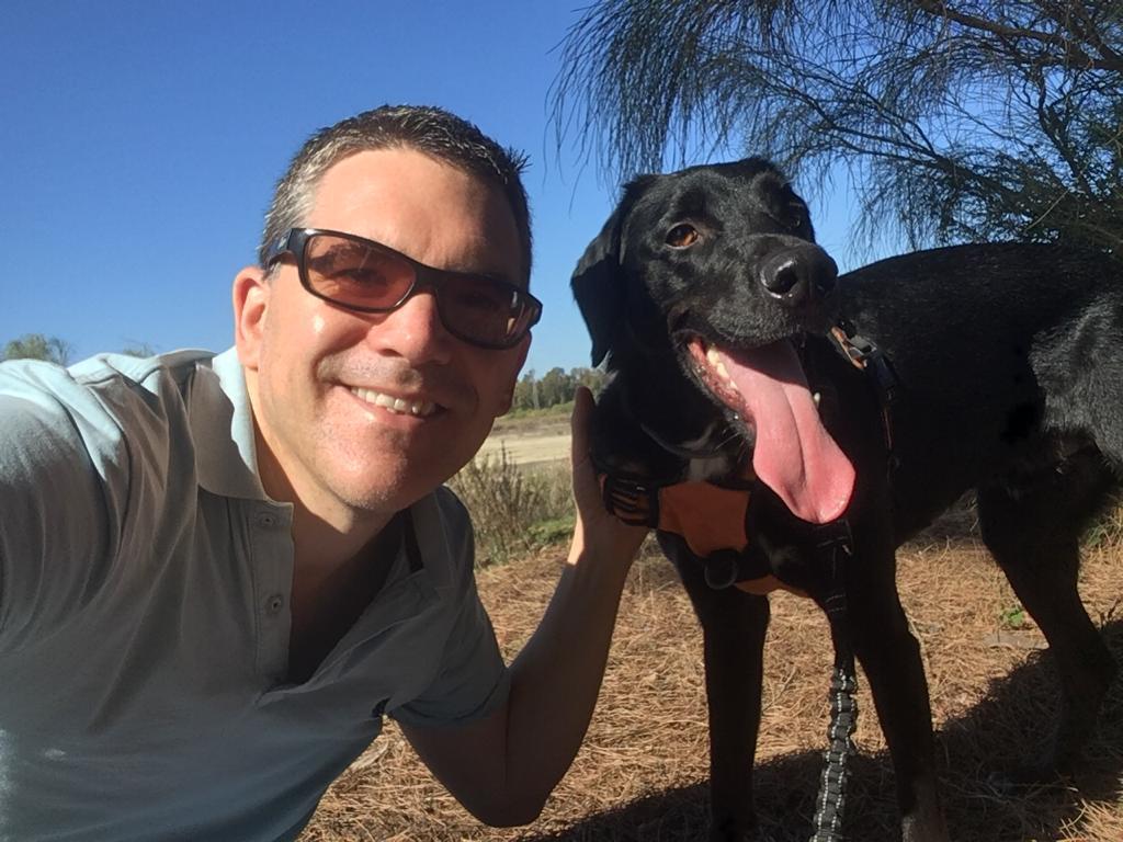 Douglas Haines and Leon the black rescue dog smiling together outdoors